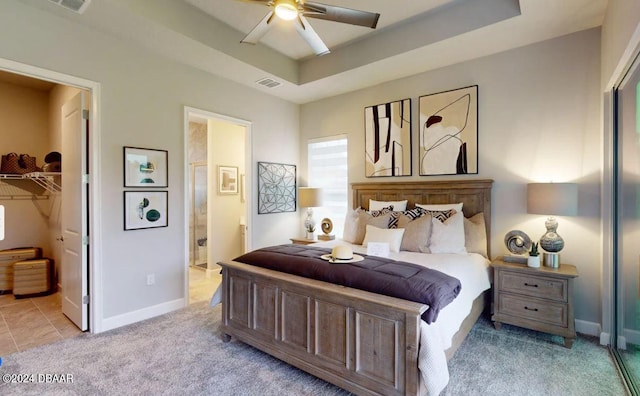 bedroom with ensuite bath, light carpet, ceiling fan, a walk in closet, and a closet