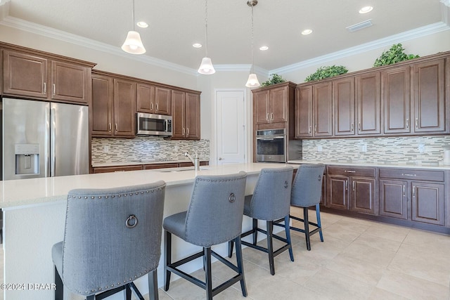 kitchen featuring ornamental molding, a center island with sink, pendant lighting, and appliances with stainless steel finishes