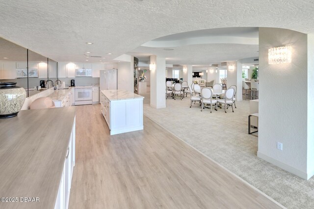 2545 S Atlantic Ave Unit 2107 2108, Daytona Beach Shores, FL 32118 - kitchen featuring a sink, white appliances, light colored carpet, a textured ceiling, and light stone counters