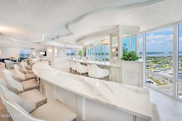 bar with light stone countertops, a textured ceiling, and light tile patterned floors