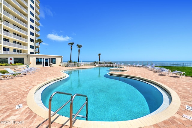 view of pool with a water view and a patio area