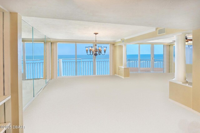 2545 S Atlantic Ave Unit 2107 2108, Daytona Beach Shores, FL 32118 - carpeted empty room featuring decorative columns, a water view, a chandelier, baseboards, and crown molding