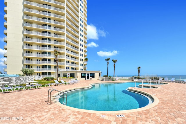 view of pool featuring a water view and a patio area