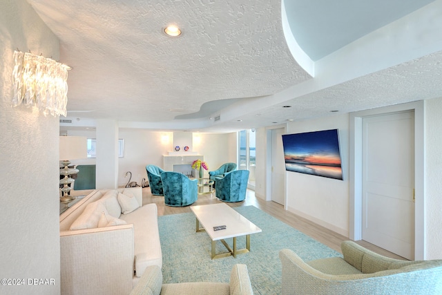 living room with an inviting chandelier, a textured ceiling, and light hardwood / wood-style flooring