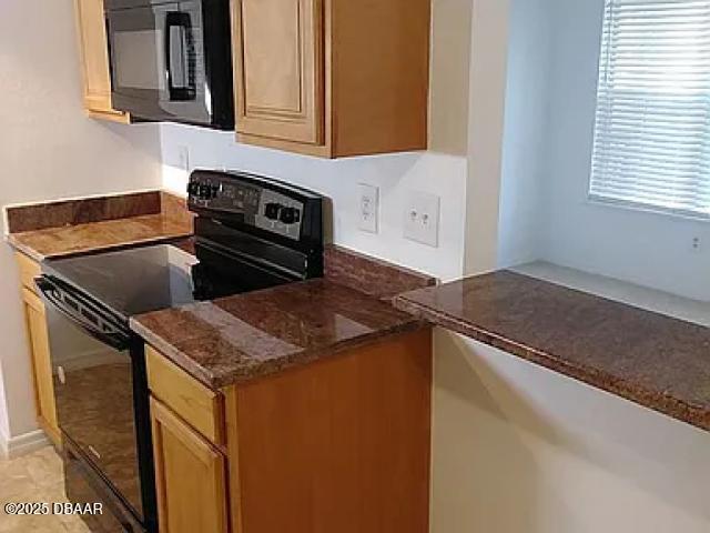 kitchen featuring dark stone counters and black appliances