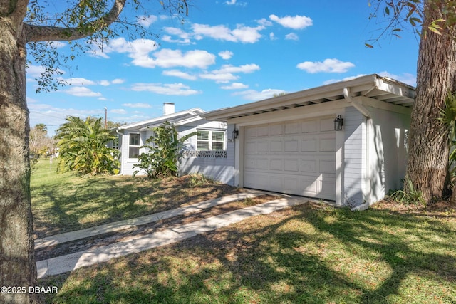 ranch-style home with a garage, brick siding, a chimney, and a front lawn