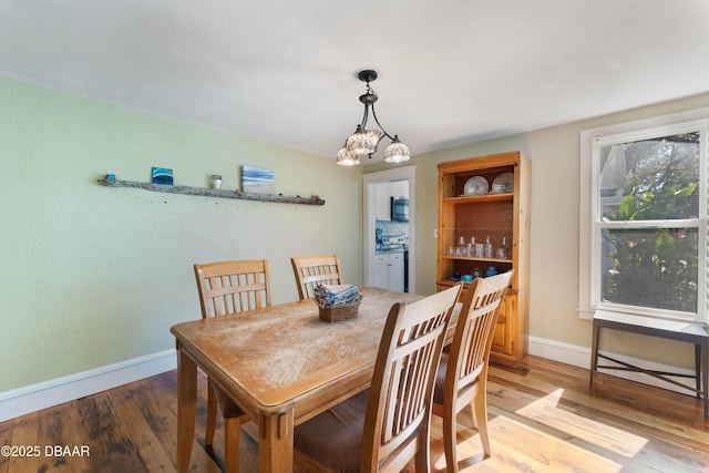 dining space with light wood-style flooring and baseboards