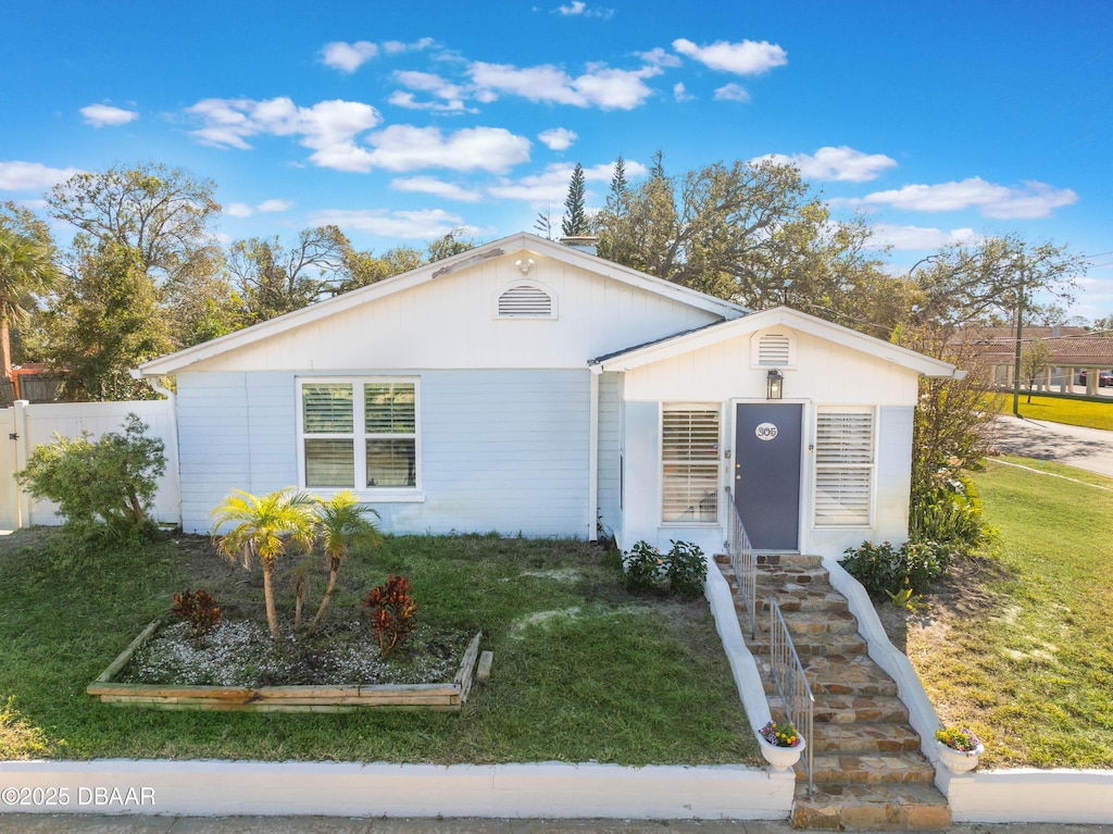 view of front of home featuring a front yard, fence, and a garden