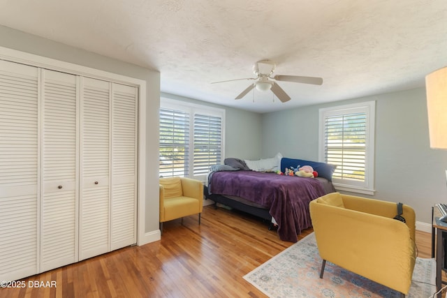 bedroom featuring a textured ceiling, wood finished floors, a ceiling fan, baseboards, and a closet