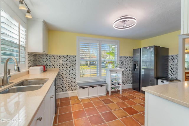 kitchen featuring stainless steel refrigerator with ice dispenser, a sink, light tile patterned flooring, and white cabinets