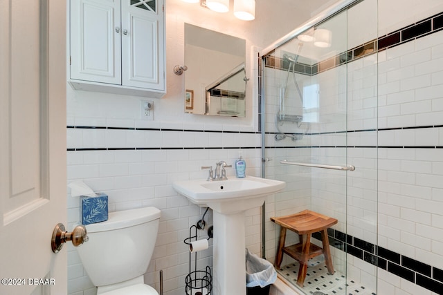 bathroom featuring toilet, tile walls, and a shower with shower door