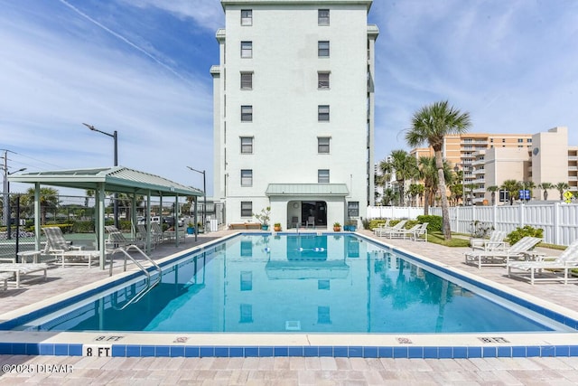 community pool with a gazebo, fence, and a patio area
