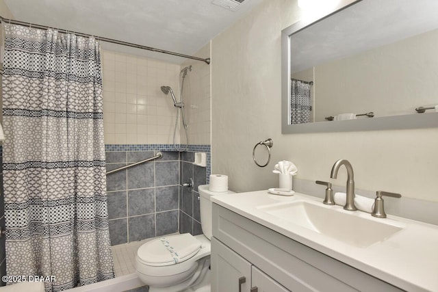 bathroom featuring toilet, vanity, and a tile shower