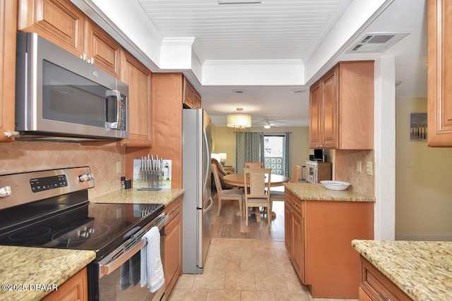 kitchen featuring stainless steel appliances, ornamental molding, brown cabinets, tasteful backsplash, and light stone counters