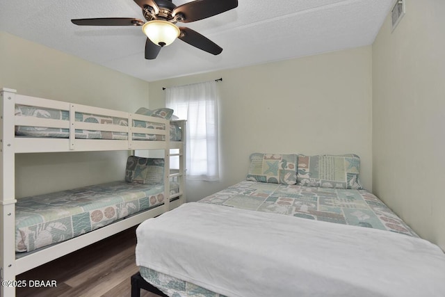 bedroom with wood finished floors, a ceiling fan, and a textured ceiling