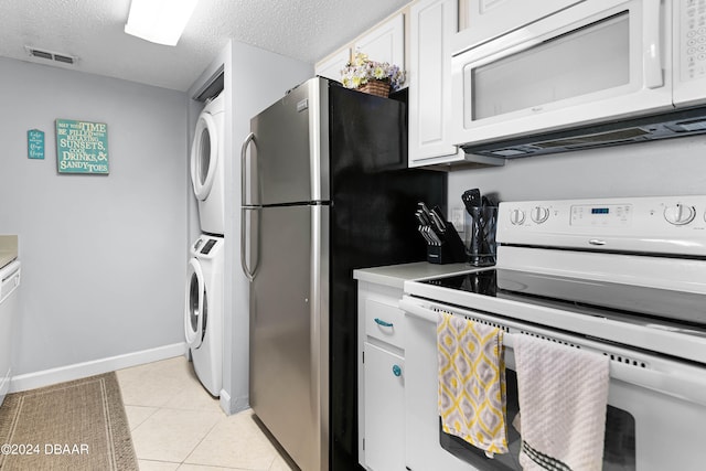 kitchen with stacked washer and clothes dryer, light tile patterned flooring, white cabinetry, a textured ceiling, and white appliances