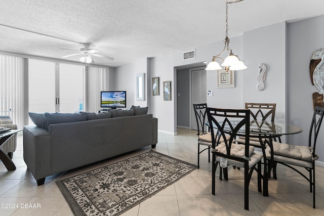 tiled living room with ceiling fan with notable chandelier and a textured ceiling