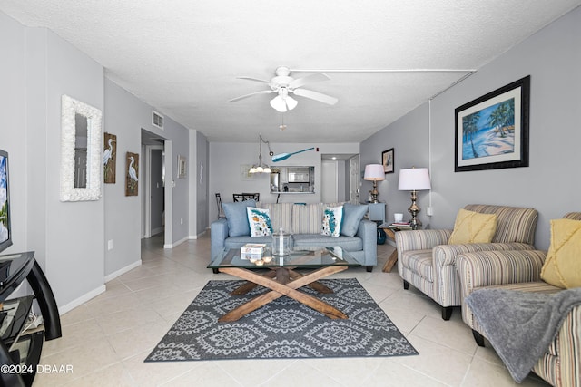 living room with ceiling fan with notable chandelier, a textured ceiling, and light tile patterned flooring