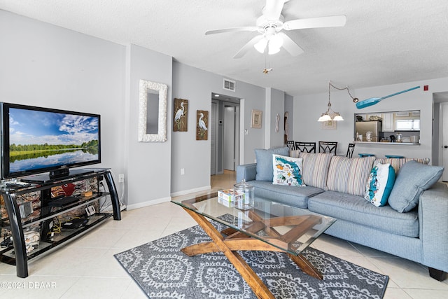 living room featuring a textured ceiling, light tile patterned floors, and ceiling fan with notable chandelier