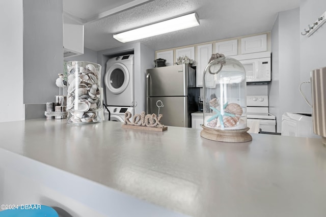 kitchen featuring stacked washing maching and dryer, kitchen peninsula, white cabinets, a textured ceiling, and white appliances