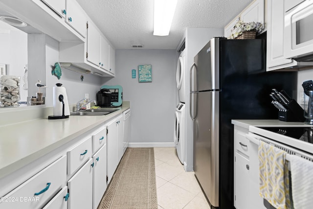 kitchen featuring white cabinets, white appliances, sink, and stacked washer / drying machine