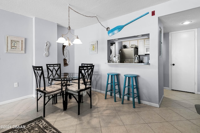 tiled dining room with a chandelier and a textured ceiling