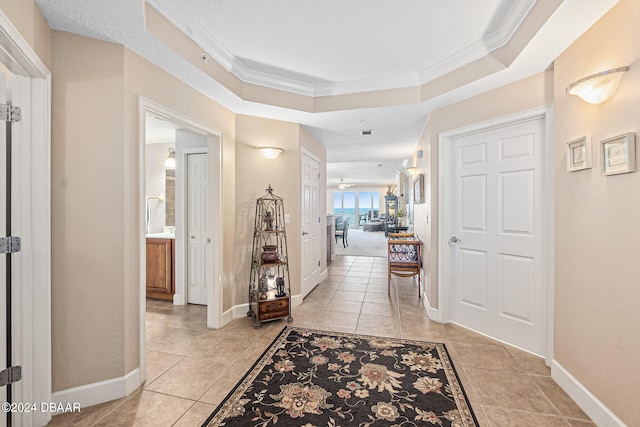 hall featuring light tile patterned floors and crown molding