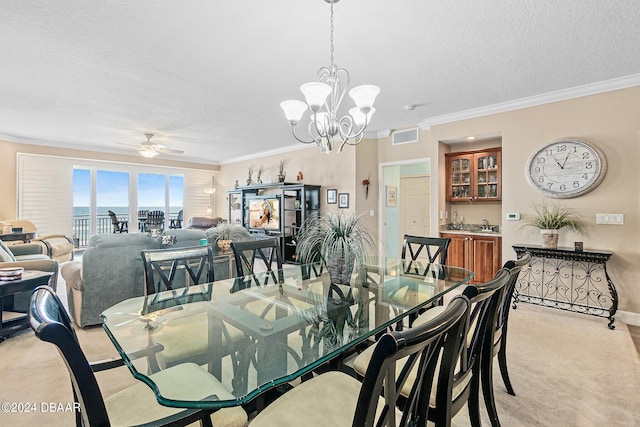 carpeted dining area with ceiling fan with notable chandelier, a textured ceiling, and crown molding