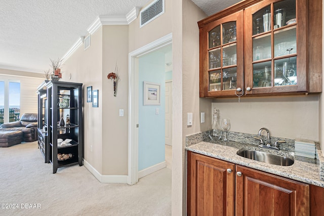 bar featuring light carpet, sink, ornamental molding, light stone countertops, and a textured ceiling