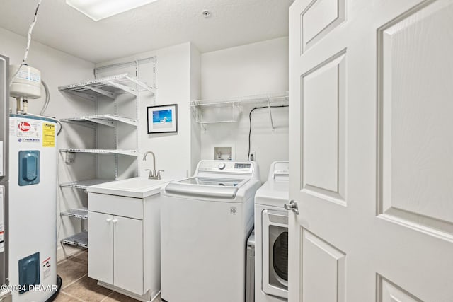 washroom featuring a textured ceiling, water heater, cabinets, sink, and washing machine and dryer