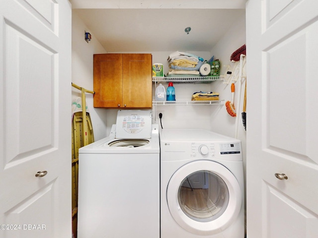 clothes washing area featuring cabinets and washer and dryer