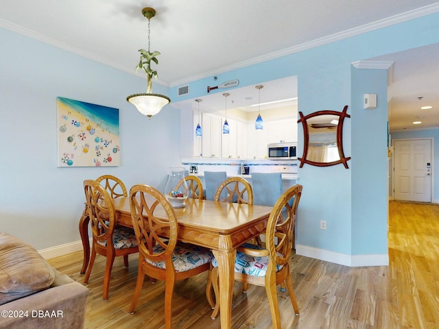 dining space with light hardwood / wood-style floors and crown molding