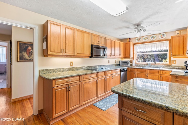 kitchen with stone countertops, a wealth of natural light, ceiling fan, and light wood-type flooring