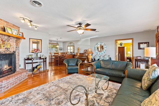 living room with hardwood / wood-style flooring, ceiling fan, a fireplace, and a textured ceiling