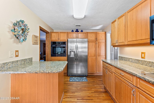 kitchen with stainless steel refrigerator with ice dispenser, light stone counters, light wood-type flooring, kitchen peninsula, and black oven