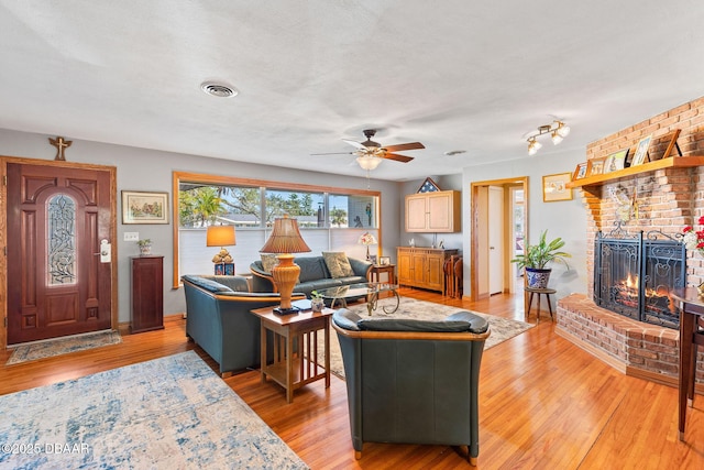 living room with ceiling fan, a fireplace, and light hardwood / wood-style flooring