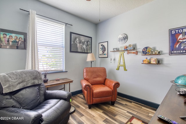 sitting room with a textured ceiling, light wood-type flooring, and baseboards