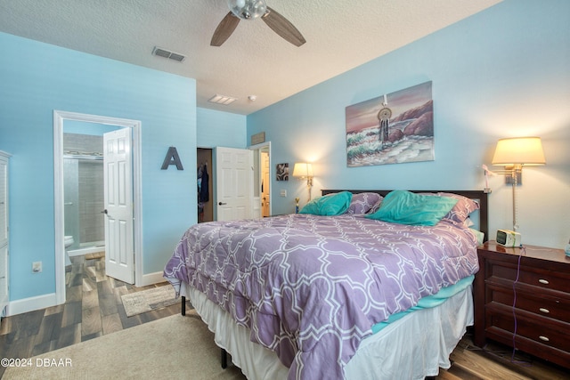 bedroom with a textured ceiling, connected bathroom, wood finished floors, visible vents, and baseboards