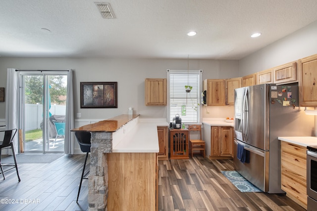 kitchen with stainless steel appliances, a healthy amount of sunlight, dark hardwood / wood-style floors, and a breakfast bar area