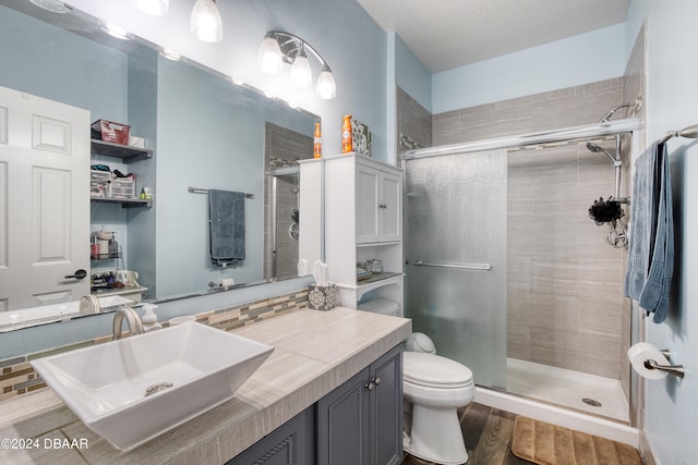 bathroom with toilet, vanity, hardwood / wood-style flooring, and a shower with door