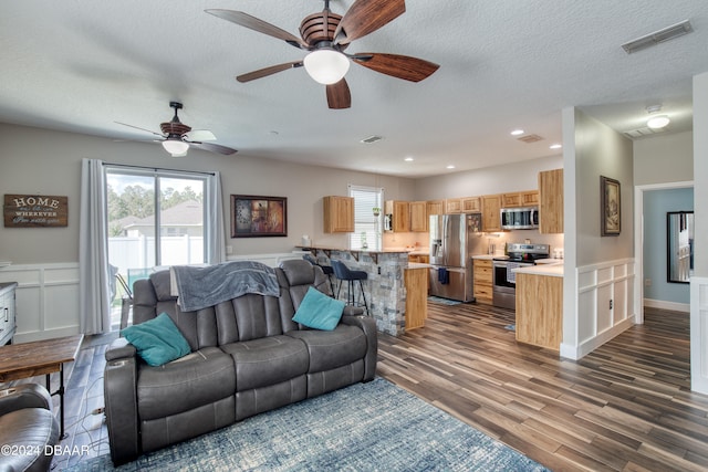 living room with dark wood-type flooring, a textured ceiling, and ceiling fan