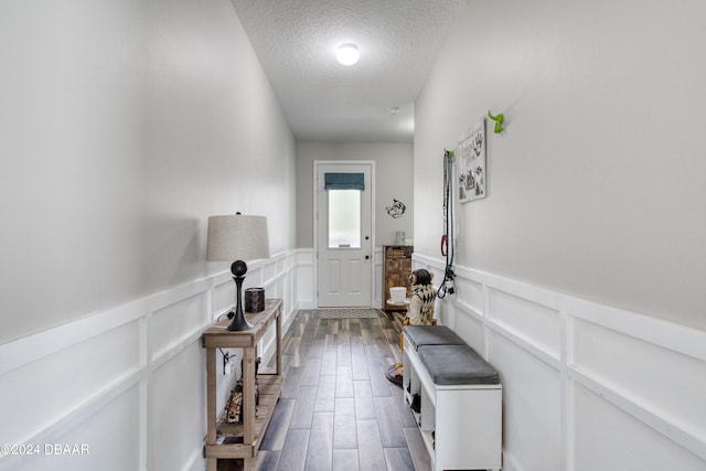 entryway featuring a textured ceiling, a decorative wall, wainscoting, and wood tiled floor