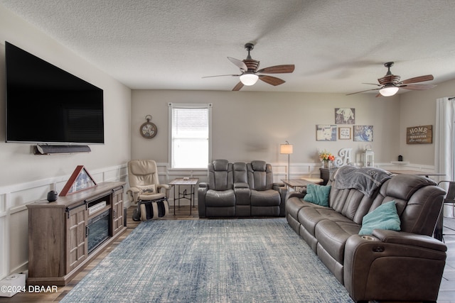 living room featuring hardwood / wood-style floors, ceiling fan, and a textured ceiling