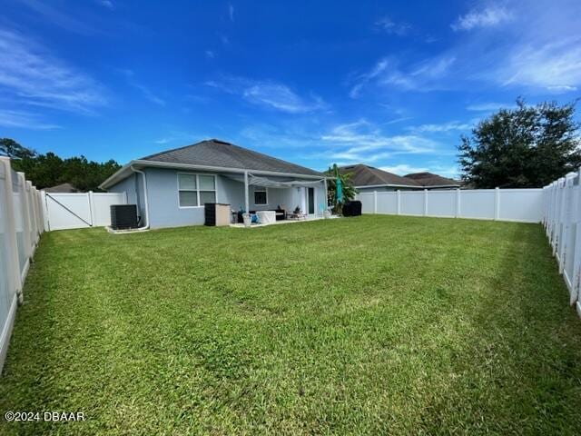 rear view of house with a lawn, cooling unit, and a fenced backyard