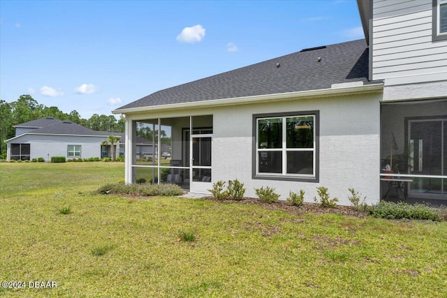 rear view of house featuring a yard and a sunroom