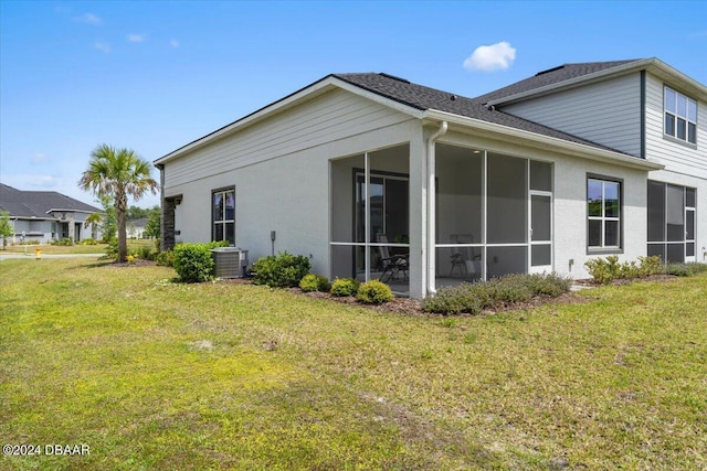 view of side of property featuring central AC unit, a lawn, and a sunroom