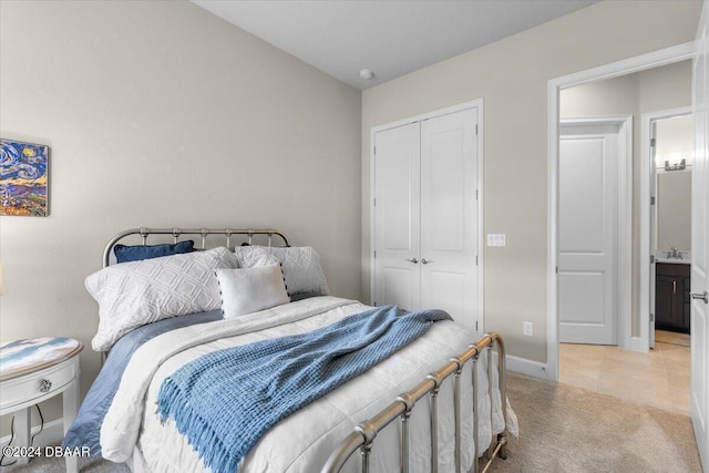 bedroom with ensuite bathroom, a closet, and light carpet