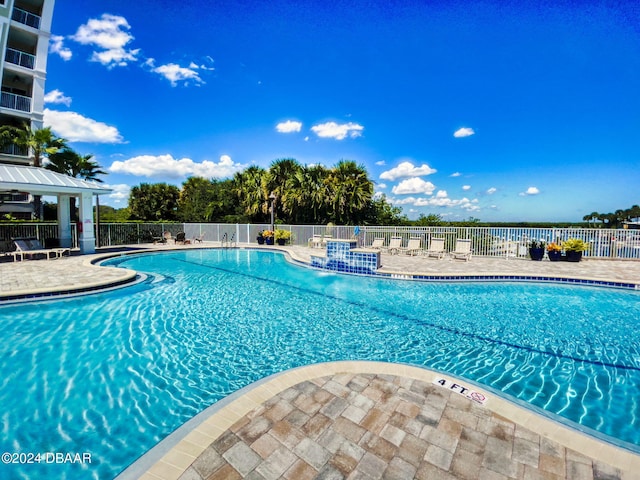 view of pool featuring a water view and a patio area