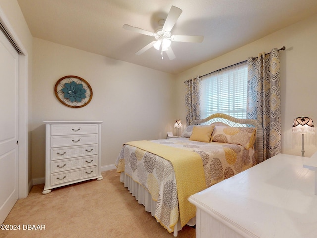 bedroom with light colored carpet, ceiling fan, and a closet