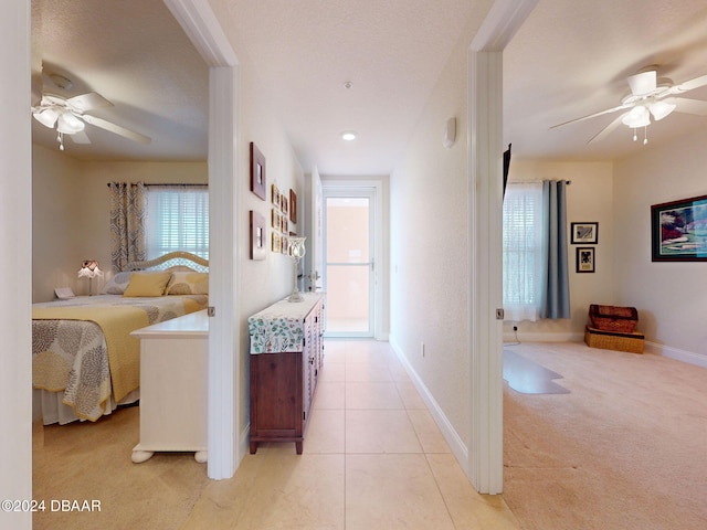 hallway featuring light colored carpet and a textured ceiling